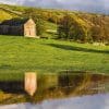 Traditional stone barn reflected in a flooded field near Kettlewell, Wharfedale, Yorkshire Dales, England.