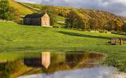 Traditional stone barn reflected in a flooded field near Kettlewell, Wharfedale, Yorkshire Dales, England.
