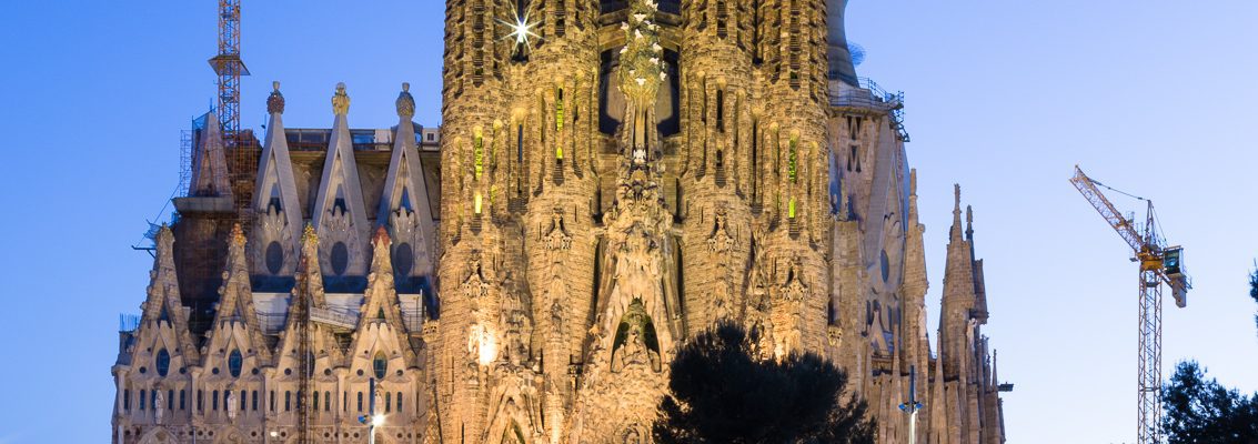Dusk view of  the Nativity Facade of La Sagra Familia basilica reflected in the lake of the Placa de Gaudi, Barcelona, Spain. BC014