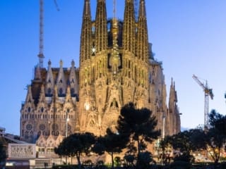Dusk view of the Nativity Facade of La Sagra Familia basilica reflected in the lake of the Placa de Gaudi, Barcelona, Spain. BC014