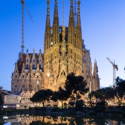Dusk view of the Nativity Facade of La Sagra Familia basilica reflected in the lake of the Placa de Gaudi, Barcelona, Spain.