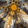 Interior view of the ceiling of La Sagra Familia basilica showing forest-like pillars and decoration as light filters through roof.