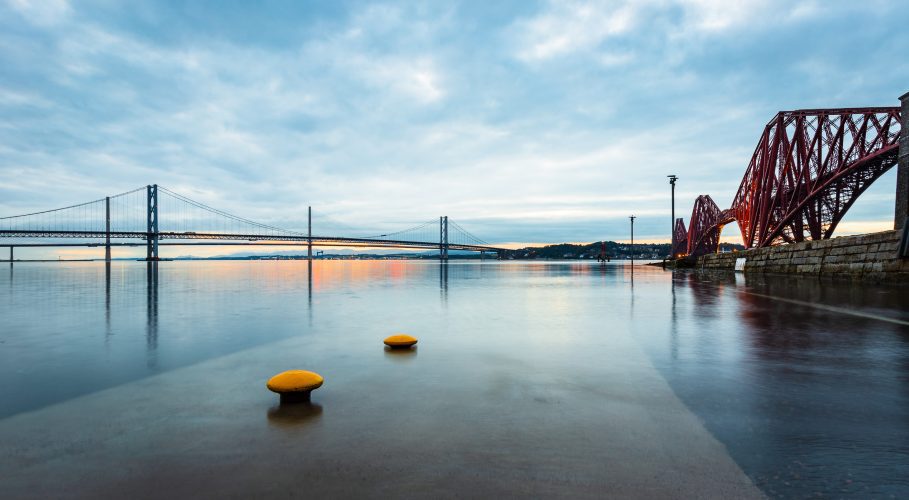 The tide washes over the Hawes Pier at South Queensferry with the Forth Bridges in the background, West Lothian, Scotland, United Kingdom. FB007