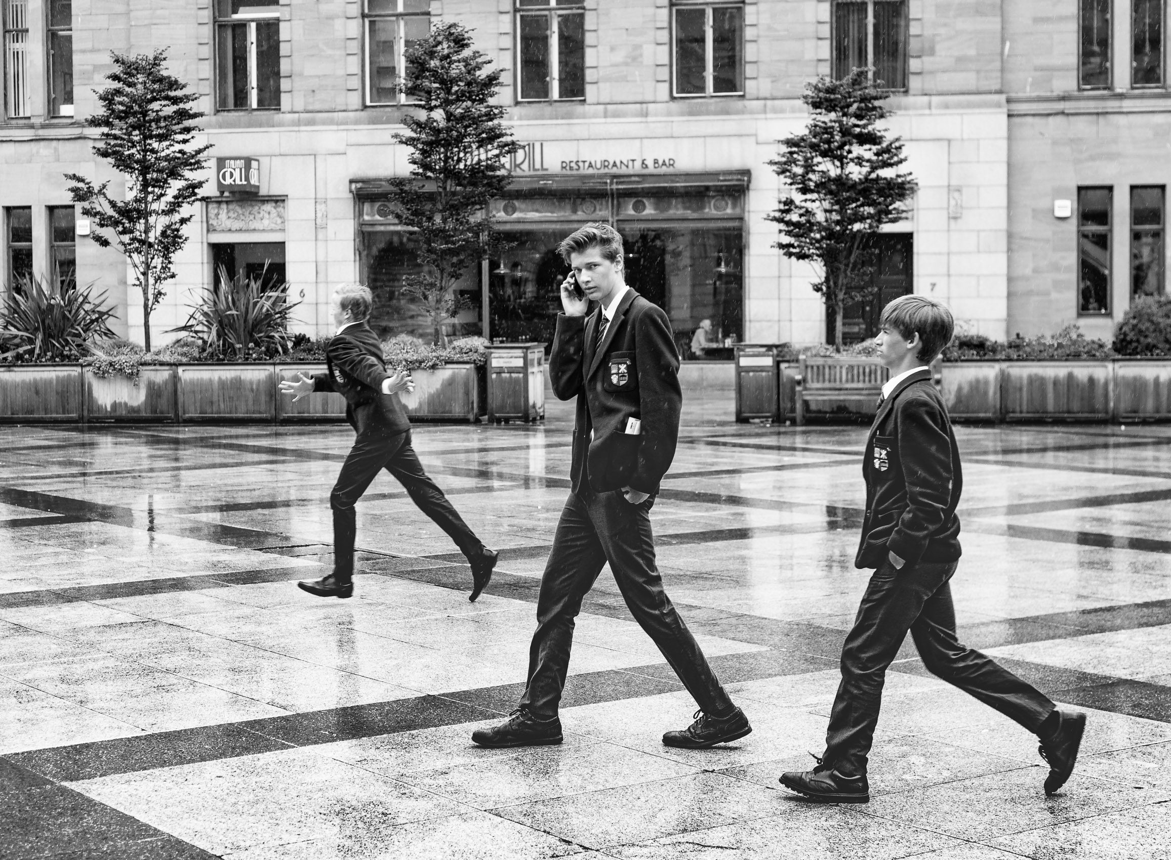 Monochrome (black and white) image of three pupils of Dundee High School in City Square, Dundee after the school's graduation ceremony in the Caird Hall. DD007
