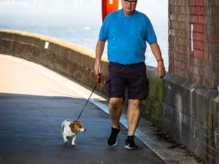 Man and dog walking under the Tay Railway Bridge, Dundee, Scotland. DD085