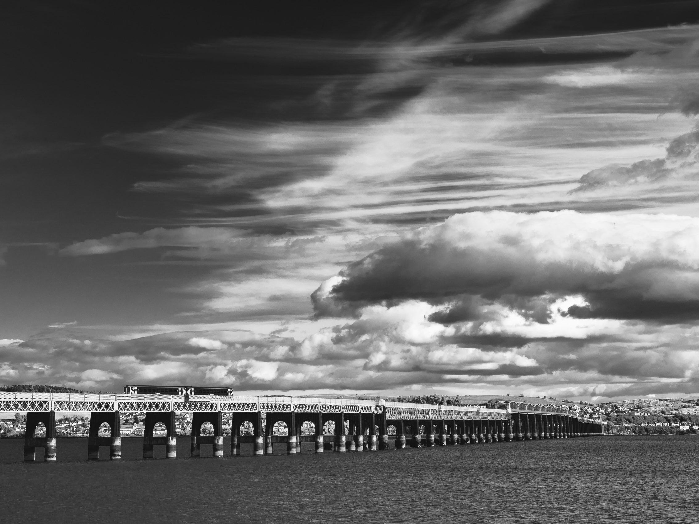 Monochrome image of clouds gathering over the Tay Rail Bridge from Dundee, Scotland. DD048