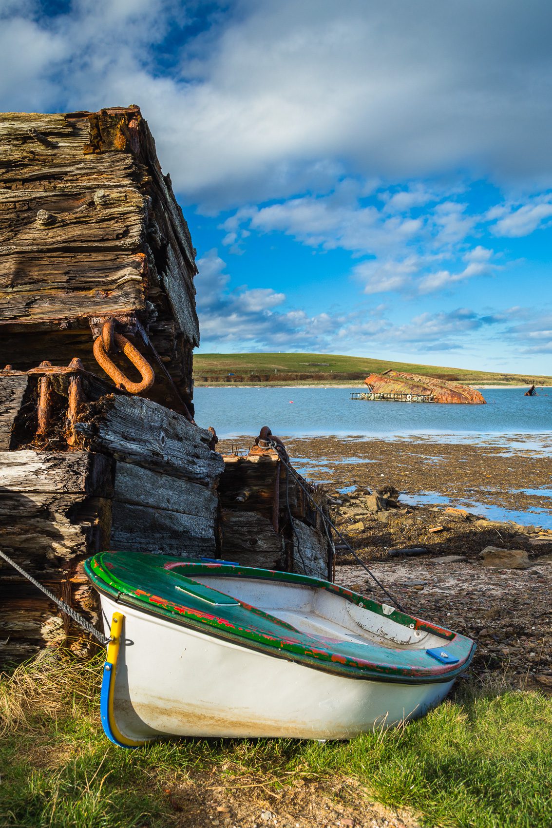 Wooden piles and beached boat between Burray and Glimps Holm, Orkney Islands. OR017