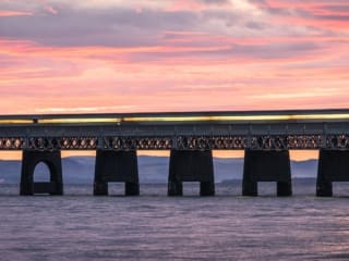 Train passing over the Tay Railway Bridge at sunset, Dundee, Scotland.